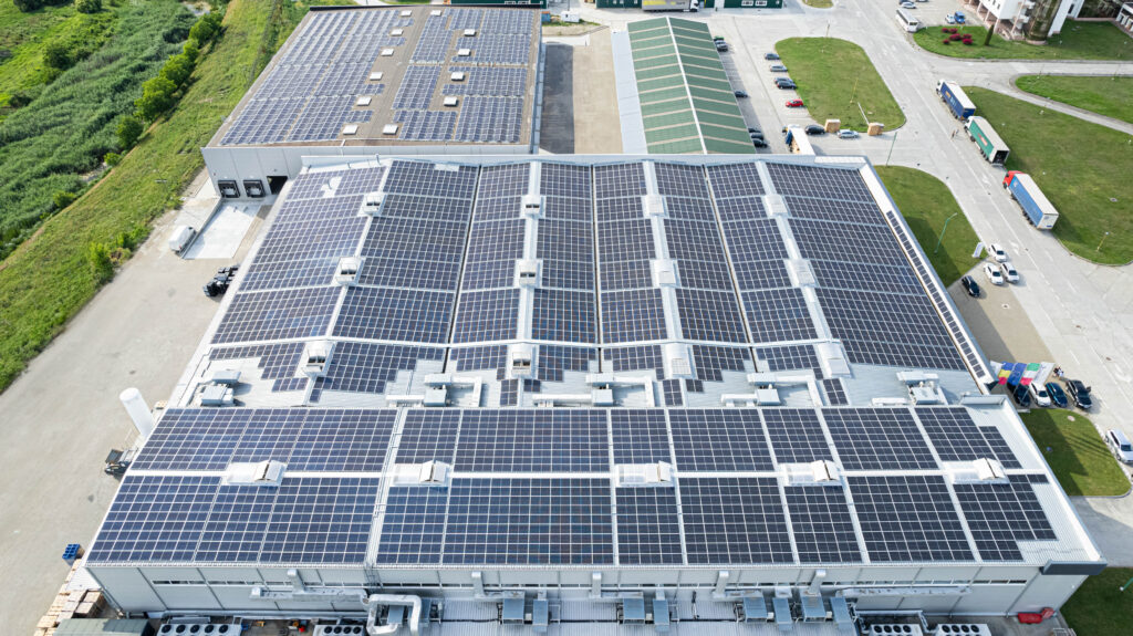 Bacau Solar Panels - Tecnostamp Triulzi Aerial view of a large industrial building covered with dense solar panels on the roof, generating solar energy